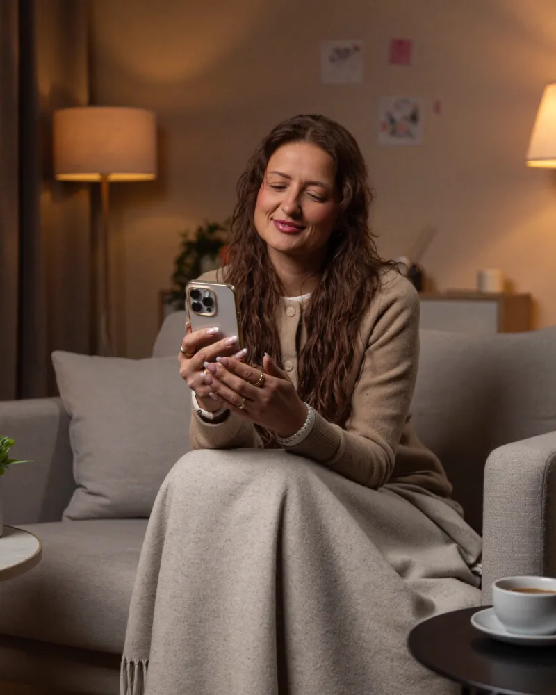 Ina schaut abends auf dem Sofa aufs Handy